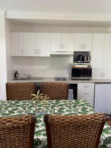 a kitchen with a table and chairs and white cabinets at Luxury Top Floor Sunset Villa in Noosaville