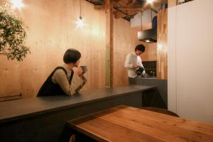 a woman sitting at a counter taking a picture of a man in the kitchen at まちの別邸 緝 shu in Kochi