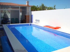 una piscina azul en una casa con una pared blanca en Villa T4 35km Montargil - Private & Heated Pool en Casal do Anafe de Baixo