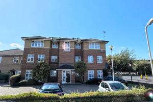 a large brick building with cars parked in a parking lot at Apartment with King Bed & Free Parking in London in Southall