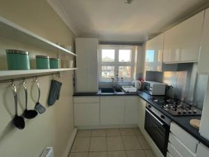 a kitchen with white cabinets and a stove top oven at Apartment with King Bed & Free Parking in London in Southall