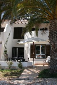 un edificio blanco con una palmera y una sombrilla en Casa de férias in RETUR, praia do Cabeço, Algarve, en Castro Marim