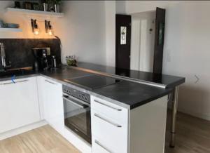 a kitchen with white cabinets and a black counter top at Ferienwohnung Caprice in Beverungen