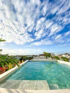 una piscina con cielo azul y nubes en Balam Suites en Playa del Carmen
