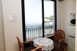 een tafel en stoelen in een kamer met een raam bij Sea View in Jeju-stad