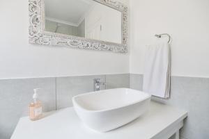 a white bathroom with a sink and a mirror at Beachcombers in Agulhas +39 photos