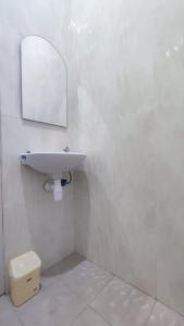 Baño blanco con lavabo y espejo en Shofa boarding house syariah, en Jenggrik