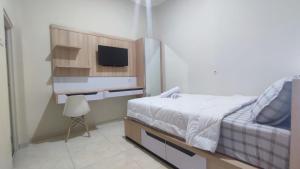 1 dormitorio con 1 cama y TV en la pared en Shofa boarding house syariah, en Jenggrik