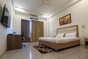a bedroom with a bed and a television in it at Hotel The Luxem - Behind Ibis Hotel Gurugram in Gurgaon