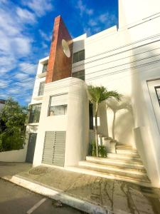 a white building with palm trees in front of it at Balam Suites in Playa del Carmen