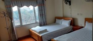 2 camas en una habitación pequeña con ventana en Nhà nghỉ hà anh 2 nội bài, en Noi Bai