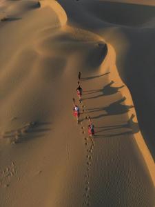 a group of people walking through the desert at Blue Eye Hostel in Jaisalmer
