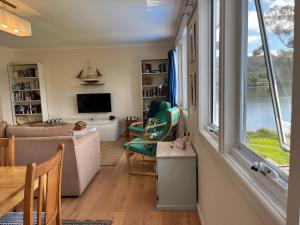 sala de estar con sofá y ventana en Anchorage Waterfront Retreat, en Castle Forbes Bay
