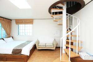 濟州的住宿－Sea View，一间卧室设有一张床和一个螺旋楼梯