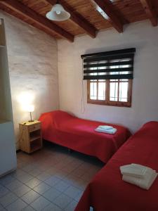 1 dormitorio con 2 camas rojas y ventana en HERMOSA CASA en la mejor zona de SAN RAFAEL en San Rafael