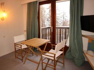 a wooden table and chairs in a room with a balcony at Appartement Les Orres, 1 pièce, 2 personnes - FR-1-322-457 in Les Orres