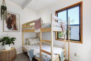 a bedroom with two bunk beds and a window at Fairview Lakeside Cottage Metung in Metung