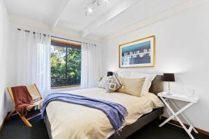 a white bedroom with a large bed and a window at Fairview Lakeside Cottage Metung in Metung