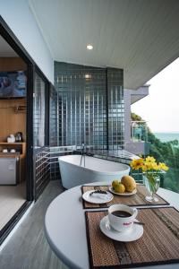 a bathroom with a tub and a table with a bowl of fruit at Cliff Lanta Suite-Koh Lanta Krabi in Ko Lanta