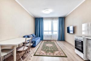 a living room with a table and chairs and a kitchen at Квартира в центре города 15-этаж in Astana