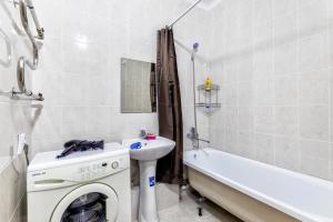 a bathroom with a washing machine next to a sink and a tub at Квартира в центре города 15-этаж in Astana
