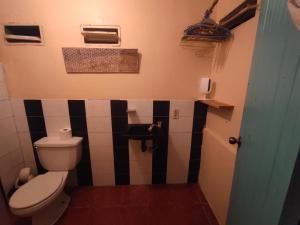 a bathroom with a toilet and black and white tiles at Alma Double Room Garden View in Rivas