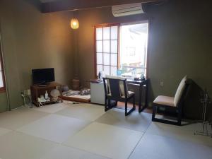 a living room with a desk and chairs and a window at Shiroyama Ryokan in Ikuma