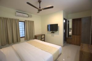 a bedroom with a bed and a flat screen tv at Elysian Grand Hotel in Bangalore