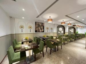 une salle à manger avec des tables et des chaises vertes dans l'établissement Skylark Hotel, à Hanoï