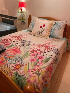 a bed with a floral comforter and a pillow at LE VIGNERON in Cilaos
