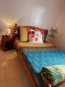 een slaapkamer met een houten bed met kussens erop bij LE VIGNERON in Cilaos