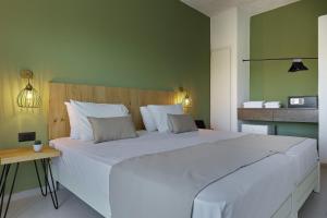 a large white bed in a room with a green wall at Charm Hotel, Hersonissos in Hersonissos