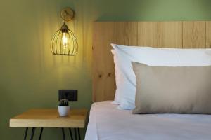 a bedroom with a bed with a white pillow and a light at Charm Hotel, Hersonissos in Hersonissos