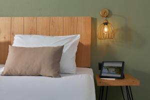 a bed with a pillow and a table with a tablet at Charm Hotel, Hersonissos in Hersonissos