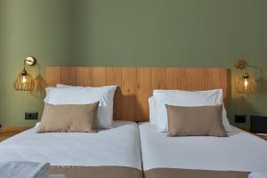 a bedroom with two beds with white sheets and pillows at Charm Hotel, Hersonissos in Hersonissos