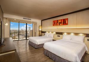 タモンにあるザ ベイビュー ホテル グアムのベッド2台と大きな窓が備わるホテルルームです。