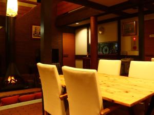 a wooden table with white chairs and a fireplace at Villa Monrepos in Myoko