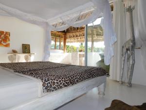 Dormitorio con cama con colcha de estampado de leopardo en Dama Villa en Watamu