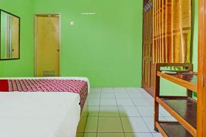 1 dormitorio con cama y pared verde en OYO 92062 Pondok Aurel Wahidin en Cirebon