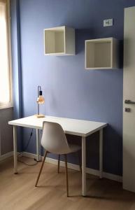 a white table with a chair and a blue wall at La casa di Anna, appartamento trilocale con balcone e garage in Brescia