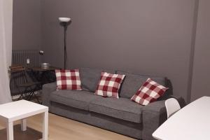 un soggiorno con divano grigio e cuscini rossi e bianchi di La casa di Anna, appartamento trilocale con balcone e garage a Brescia