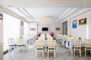 un salón de banquetes con mesas y sillas blancas en Manifa Hotel, en Tashkent