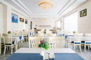 une salle à manger avec des tables et des chaises blanches dans l'établissement Manifa Hotel, à Tachkent