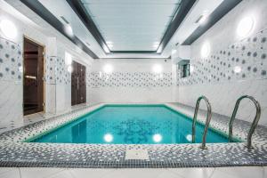 a swimming pool in a white bathroom with a tub at Manifa Hotel in Tashkent