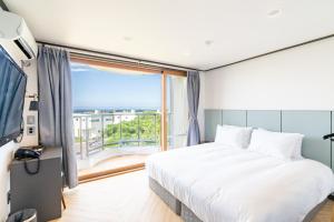 a bedroom with a large bed and a large window at Eco Green Resort & Pool Villa in Jeju