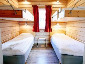 Duas camas num quarto com paredes de madeira e cortinas vermelhas em First Camp Ansia - Lycksele em Lycksele