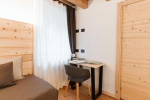 1 dormitorio con escritorio, silla y cama en Pimont Alpine Chalet, en Madonna di Campiglio