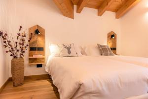 a bedroom with a white bed and a vase with flowers at B&B El Lares - B&B L'Avez in Canale dʼAgordo
