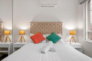 1 dormitorio con cama blanca y almohadas coloridas en StayCentral - Brunswick Vibe Parkville, en Melbourne