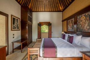 a bedroom with a bed and a table and a window at Puri Saraswati Dijiwa Ubud in Ubud